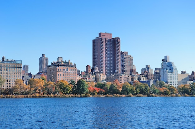 Central Park Otoño con los rascacielos del horizonte de Manhattan Midtown de la ciudad de Nueva York sobre el lago con follaje colorido y cielo azul claro.