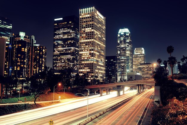 El centro de Los Ángeles por la noche con edificios urbanos y senderos ligeros