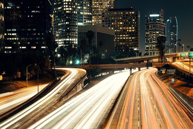 El centro de Los Ángeles por la noche con edificios urbanos y senderos ligeros