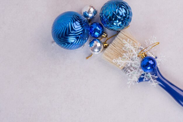 Cepillo azul con bolas de Navidad sobre superficie blanca