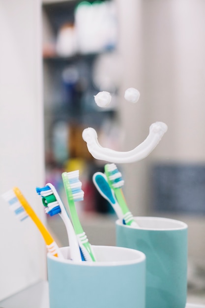 Cepillo de dientes en taza con sonrisa en el espejo