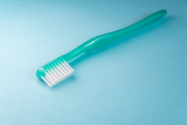 Cepillo de dientes verde sobre la mesa azul