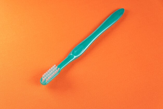 Cepillo de dientes verde sobre la mesa naranja