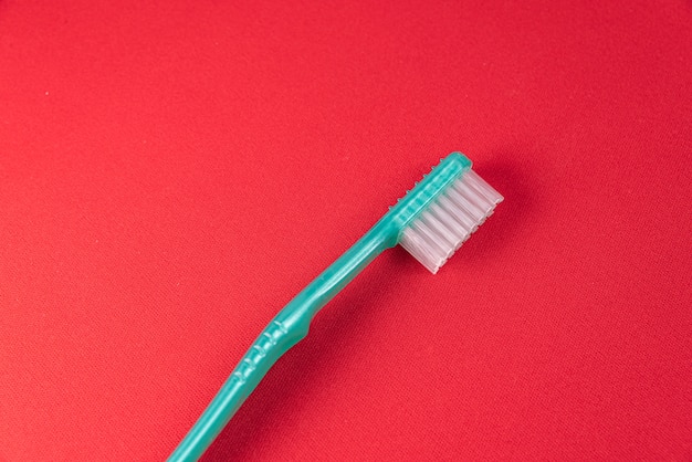 Foto gratuita cepillo de dientes verde sobre la mesa roja