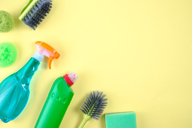 Cepillo, matorrales y botellas de detergente sobre fondo amarillo