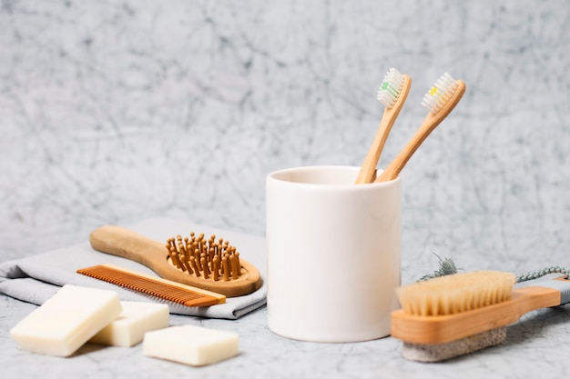 Foto gratuita cepillos de dientes en taza y cepillo de pelo natural