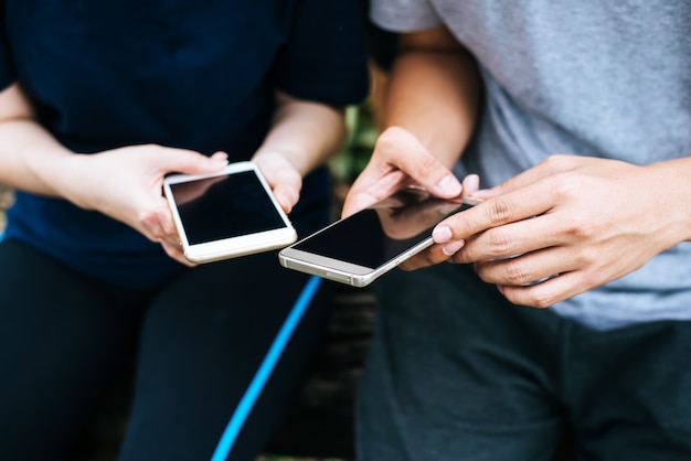 Cerca de amigos manos juegan con teléfono inteligente juntos.