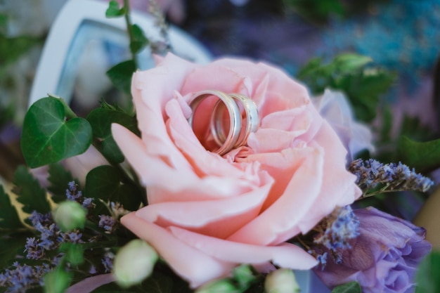 Cerca de anillos de boda en un ramo de rosas