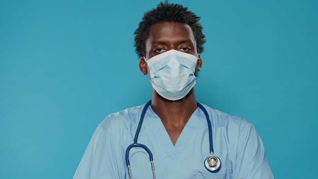 Cerca de asistente médico con mascarilla mirando a la cámara