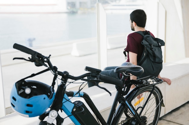 Cerca de bicicleta eléctrica con hombre sentado en el fondo