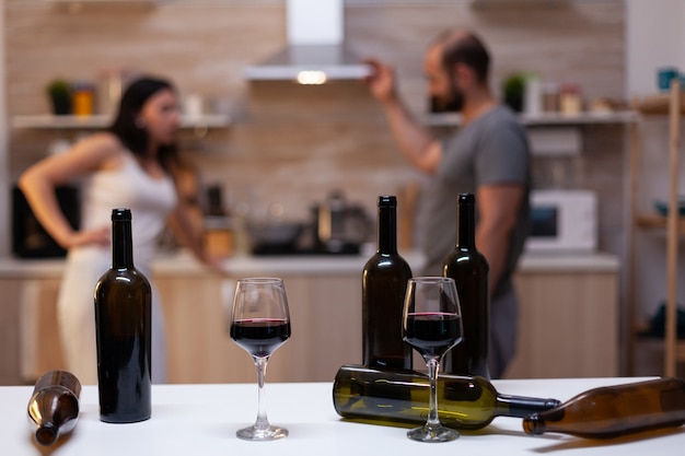 Cerca de botellas y vasos llenos de vino, licor, alcohol y bebidas alcohólicas para adictos al alcohol en el chat de fondo. Personas borrachas intoxicadas con adicción malsana