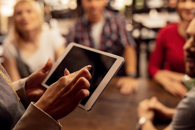 Foto gratuita cerca de una camarera irreconocible que usa una tableta digital mientras recibe pedidos de clientes en un bar