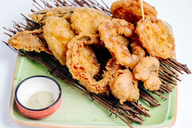 Cerca de crujientes mariscos fritos servidos en stick board en fondo blanco.