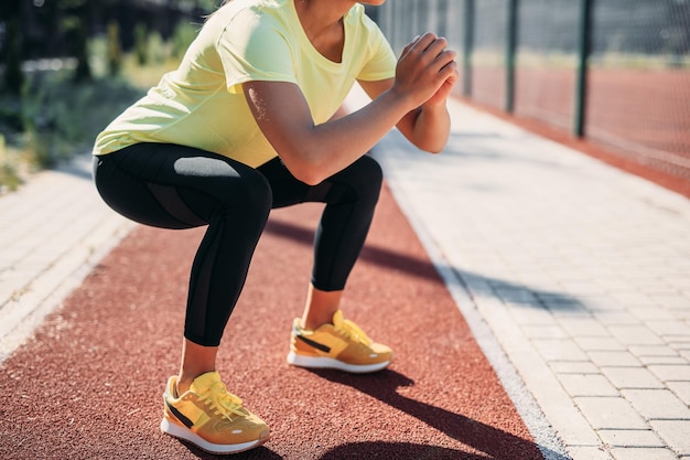 Cerca de deportista haciendo ejercicios de sentadillas en la corte