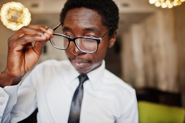 Cerca del desgaste del hombre afroamericano de negocios en camisa blanca corbata y gafas en la oficina