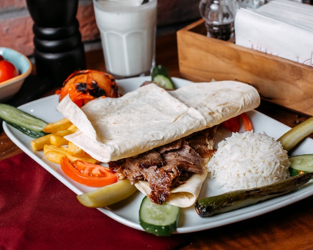 Cerca de doner carne con papas fritas arroz y verduras en placa