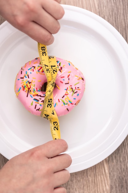 Foto gratuita cerca de donut y cinta métrica concepto de dieta y pérdida de peso