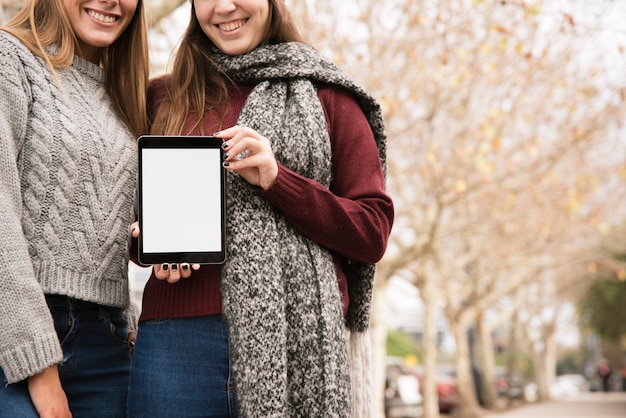 Cerca de dos mujeres elegantes con tableta en manos