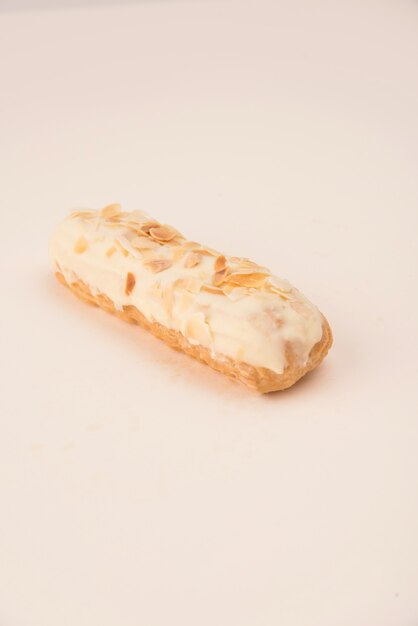 Cerca de eclair con crema blanca y nueces aisladas sobre blanco