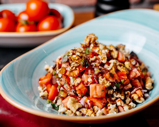 Cerca de ensalada fresca picada con tomates pimientos hierbas y nueces en un plato