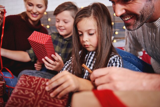 Cerca de la familia abriendo regalos de Navidad en la cama