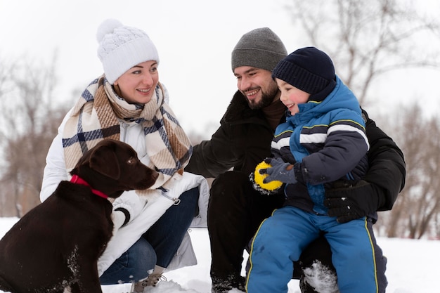 Foto gratuita cerca de familia feliz jugando en la nieve con perro