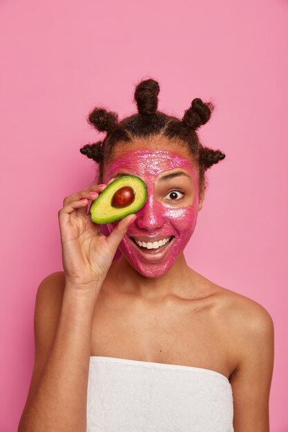 Cerca de feliz mujer étnica disfruta aplicando mascarilla aislada