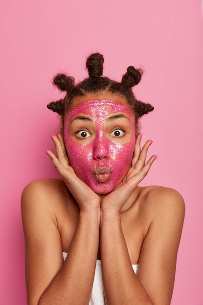 Cerca de feliz mujer étnica disfruta aplicando mascarilla aislada