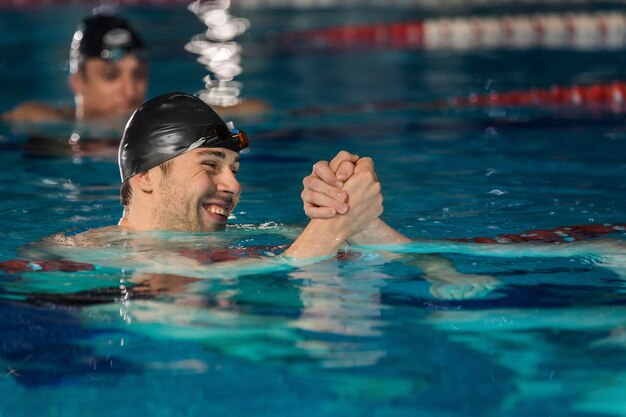 Cerca de feliz nadador masculino agitando otra mano de nadadores