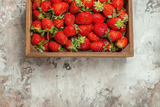 Cerca de fresas frescas en una pequeña caja de madera marrón