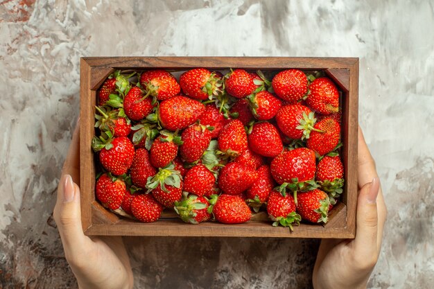 Cerca de fresas frescas en una pequeña caja de madera marrón