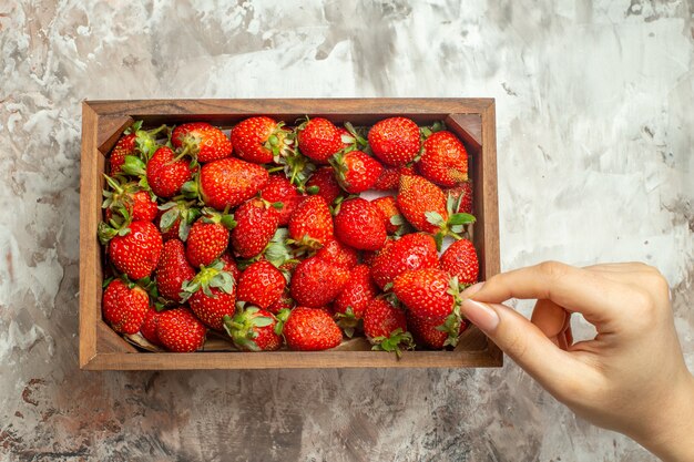 Cerca de fresas frescas en una pequeña caja de madera marrón