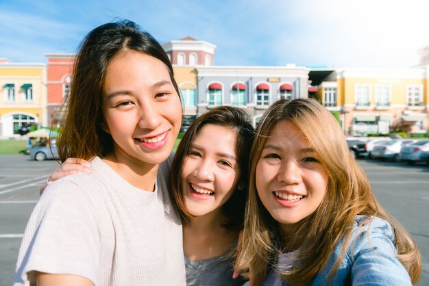 Cerca del grupo de mujeres asiáticas jóvenes autofoto ellos mismos en la ciudad edificios de pastel