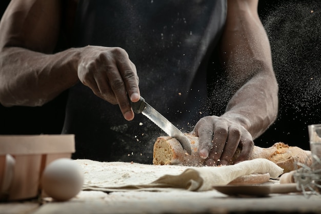 Cerca de hombre afroamericano rebanadas de pan fresco con un cuchillo de cocina