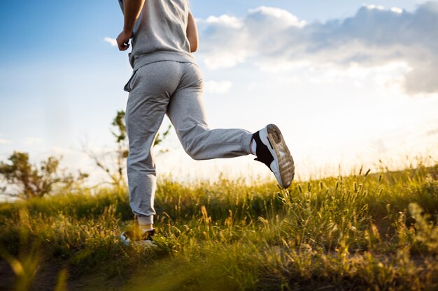 Cerca del hombre deportivo para correr en el campo al amanecer.