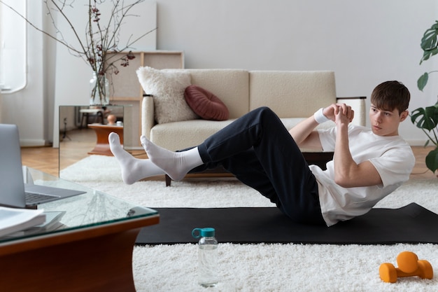 Foto gratuita cerca del hombre haciendo ejercicio después del instructor en línea