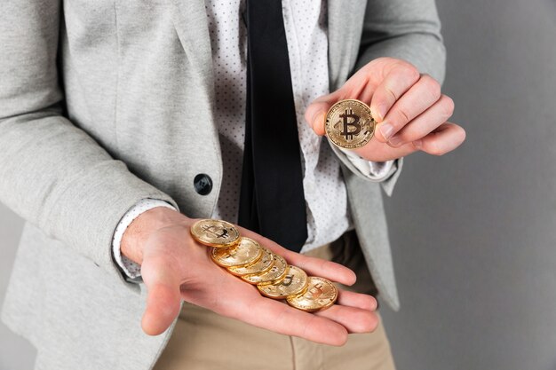 Cerca del hombre que sostiene la pila de bitcoins dorados