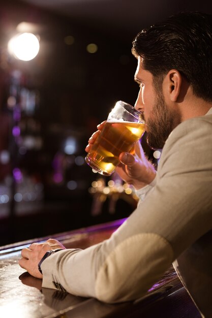 Cerca de un hombre que sostiene un vaso de cerveza