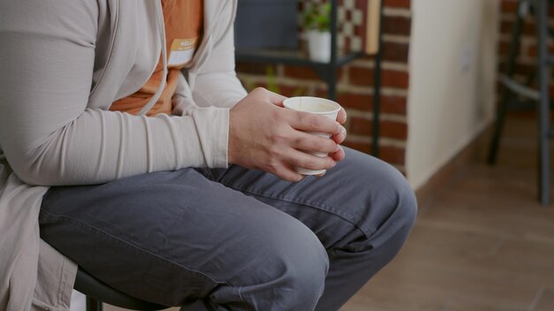 Cerca de un hombre temblando y sosteniendo una taza de café en una reunión de terapia. Persona con manos temblorosas que asiste a una sesión de rehabilitación para curar problemas de salud mental y adicción al alcohol.