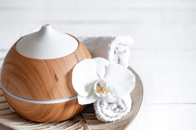 Cerca del humidificador de aire, toalla y flor de orquídea. Concepto de aromaterapia y cuidado y salud.