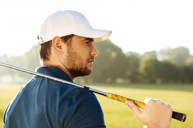 Cerca de un joven golfista masculino guapo con sombrero