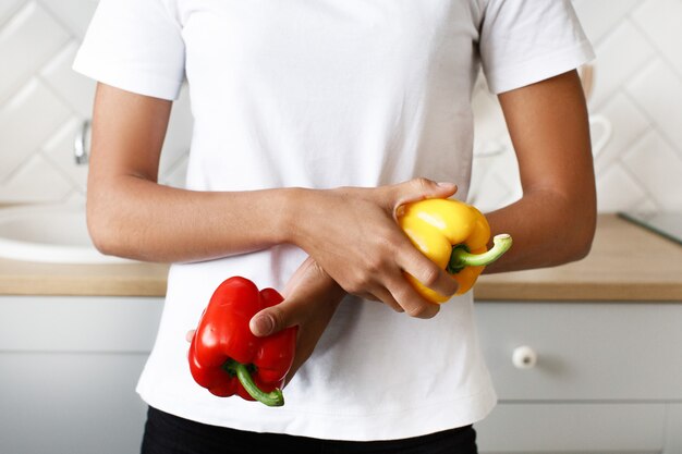 De cerca, joven tiene dos pimiento amarillo y rojo