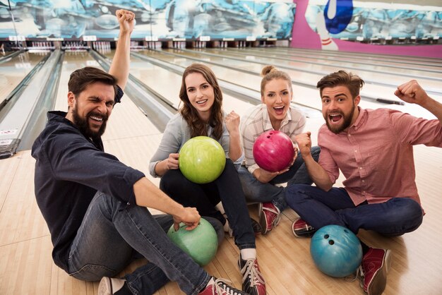 Cerca de jóvenes amigos disfrutando de los bolos