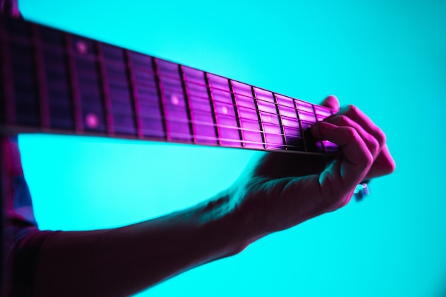 Cerca de la mano del guitarrista tocando la guitarra, macro. Concepto de publicidad, afición, música, festival, entretenimiento. Persona que improvisa inspirada. Copyspace para insertar imagen o texto. Neón colorido iluminado.