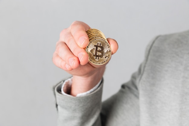 Cerca de la mano masculina que muestra bitcoin dorado