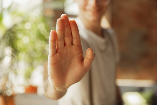 Cerca de la mano masculina que muestra signos de detenerse, rechazar. Concepto de educación, autónomos, negocios y comunicación. Modelo masculino caucásico en el interior invitando, mostrando. Copyspace para anuncio.