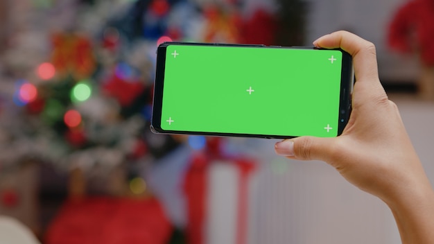 Cerca de la mano que sostiene la pantalla verde horizontal en el teléfono inteligente