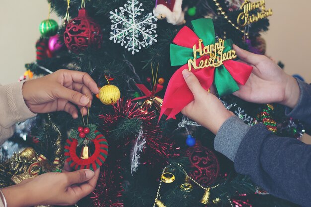 Cerca de las manos ayudando a decorar el árbol de Navidad