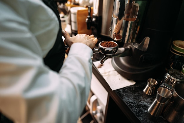 Cerca de las manos del barista preparando café para el cliente en la cafetería.