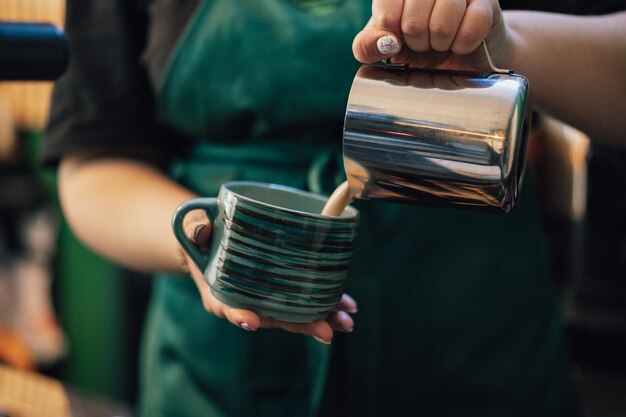 Cerca de las manos del barista preparando café para el cliente en la cafetería.